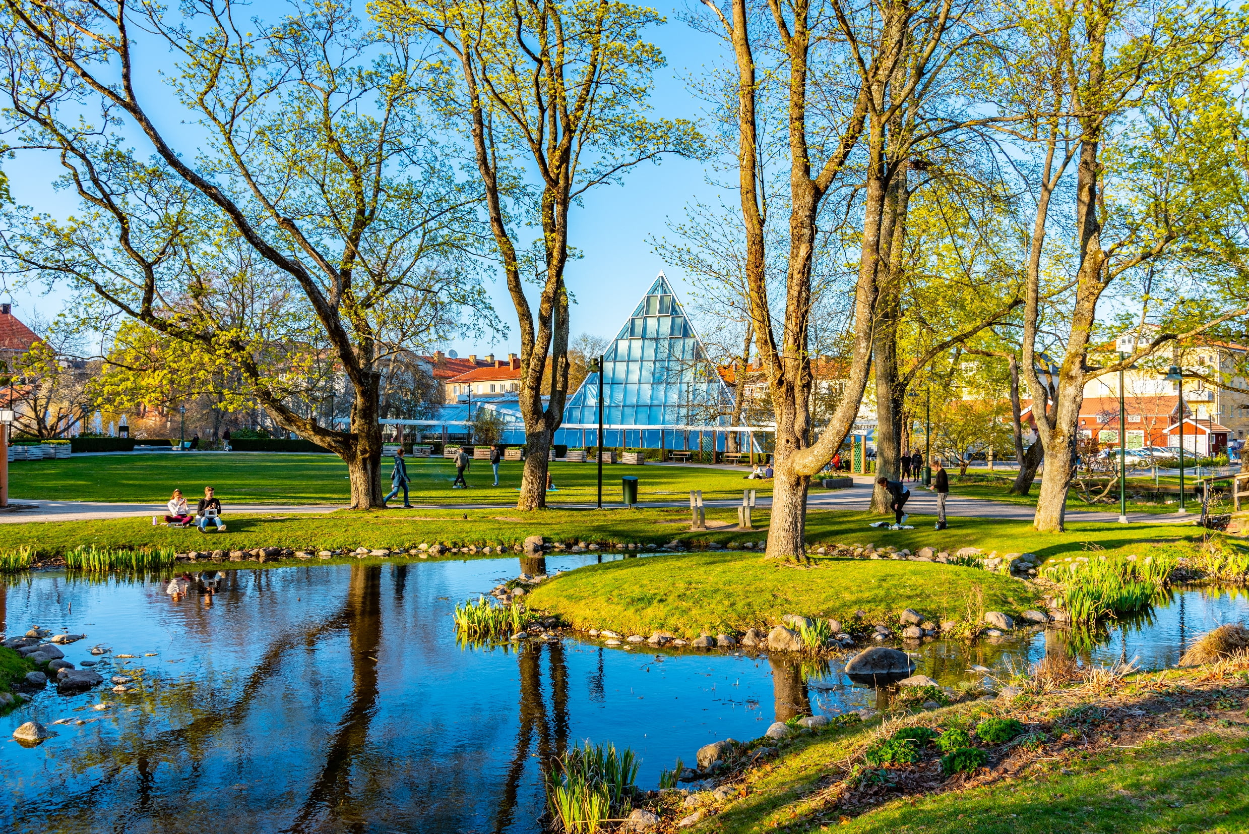 Visar en park i Linköping med ett stort växthus i mitten